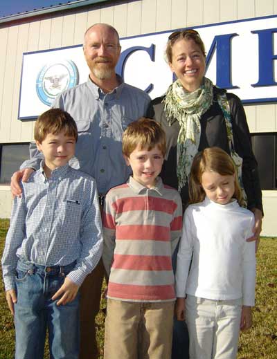 Family of 5 smiling in front of a building. 