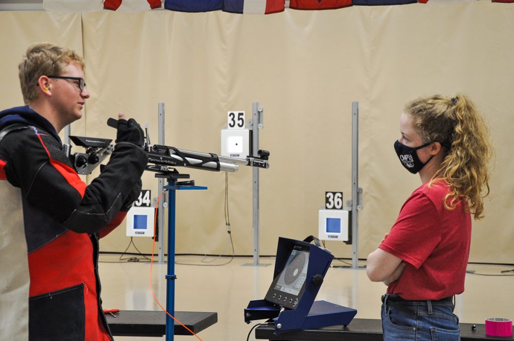 CMP camp counselor on the firing line with junior air rifle competitor.