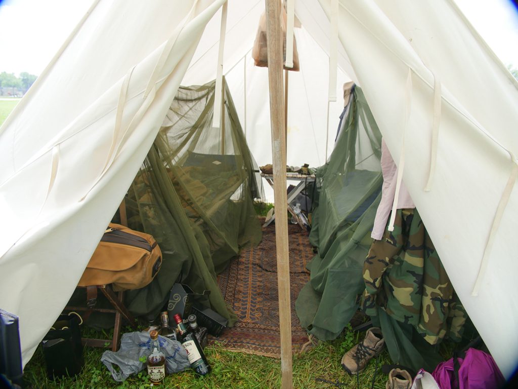 Inside of a tent with two cots covered in mosquito netting.