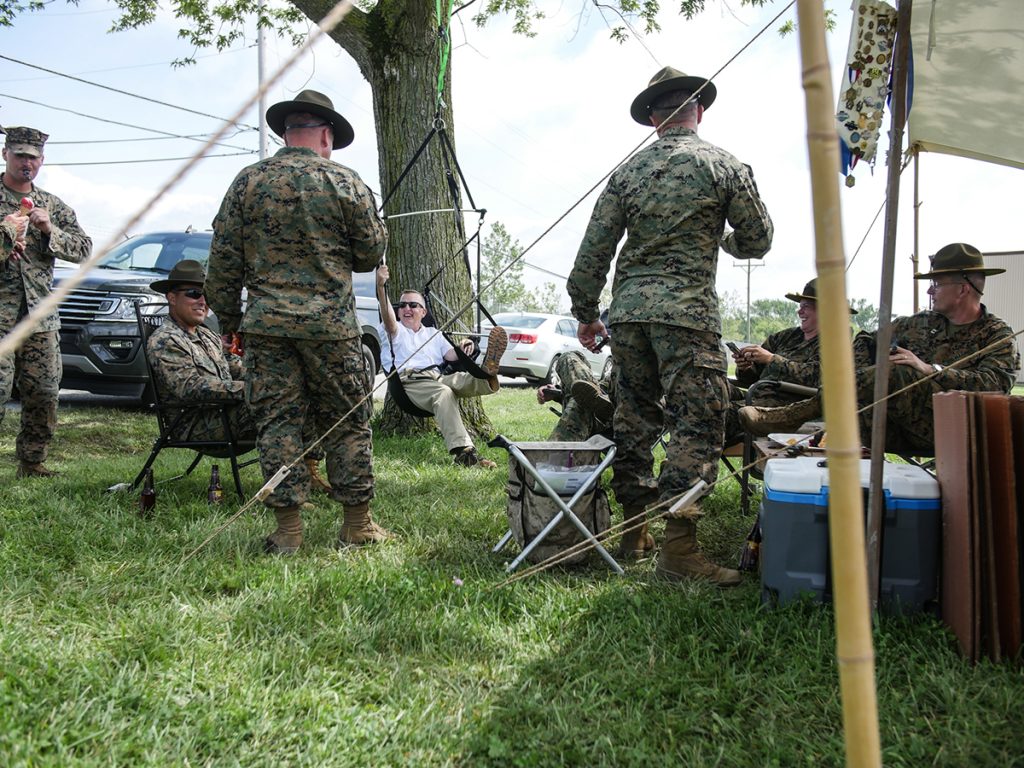 Marines standing around a tree at a campsite. 