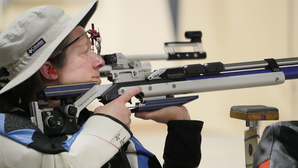 Precision rifle competitor aiming downrange.