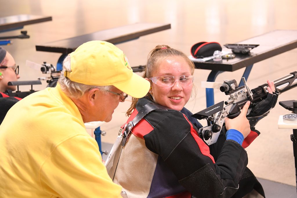 Certified instructor is coaching on the air rifle firing line during the Junior Smallbore and Air Rifle Camp