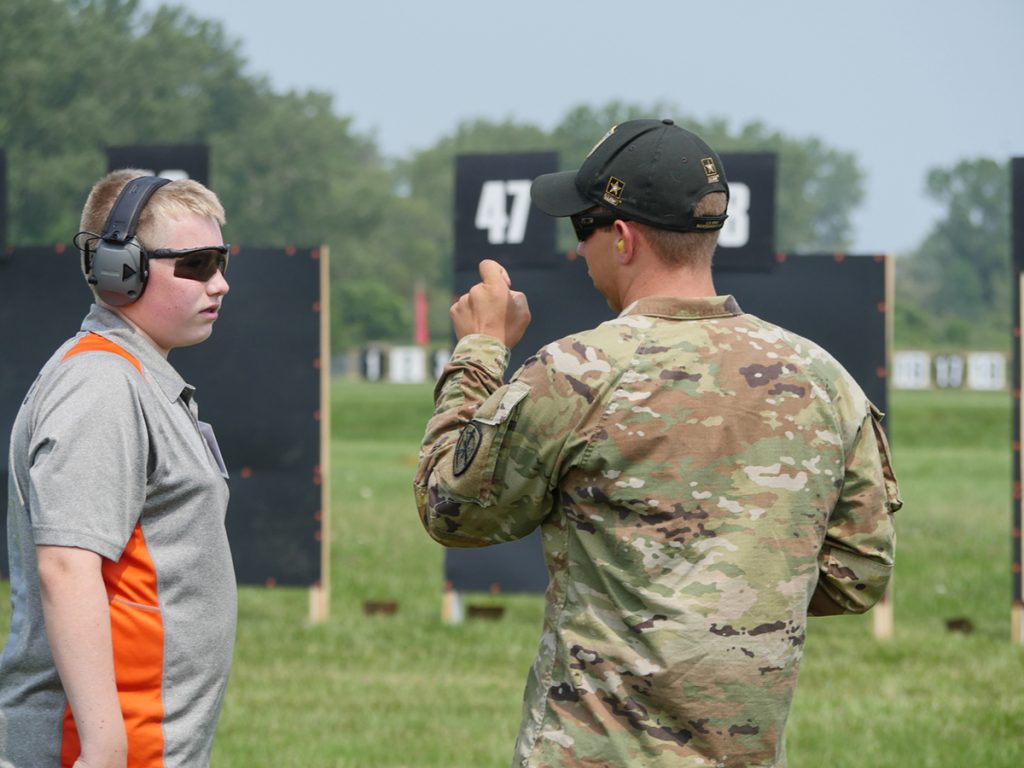 A member of the USAMU Rifle Team helps to explain trigger control to a student during the Small Arms Firing School