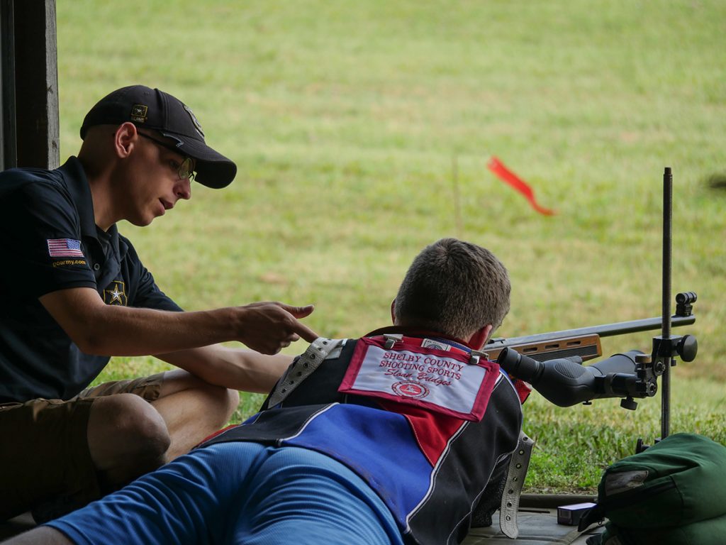 A member of the USAMU Rifle Team helps instruct the prone position to a student in the Small Arms Firing School