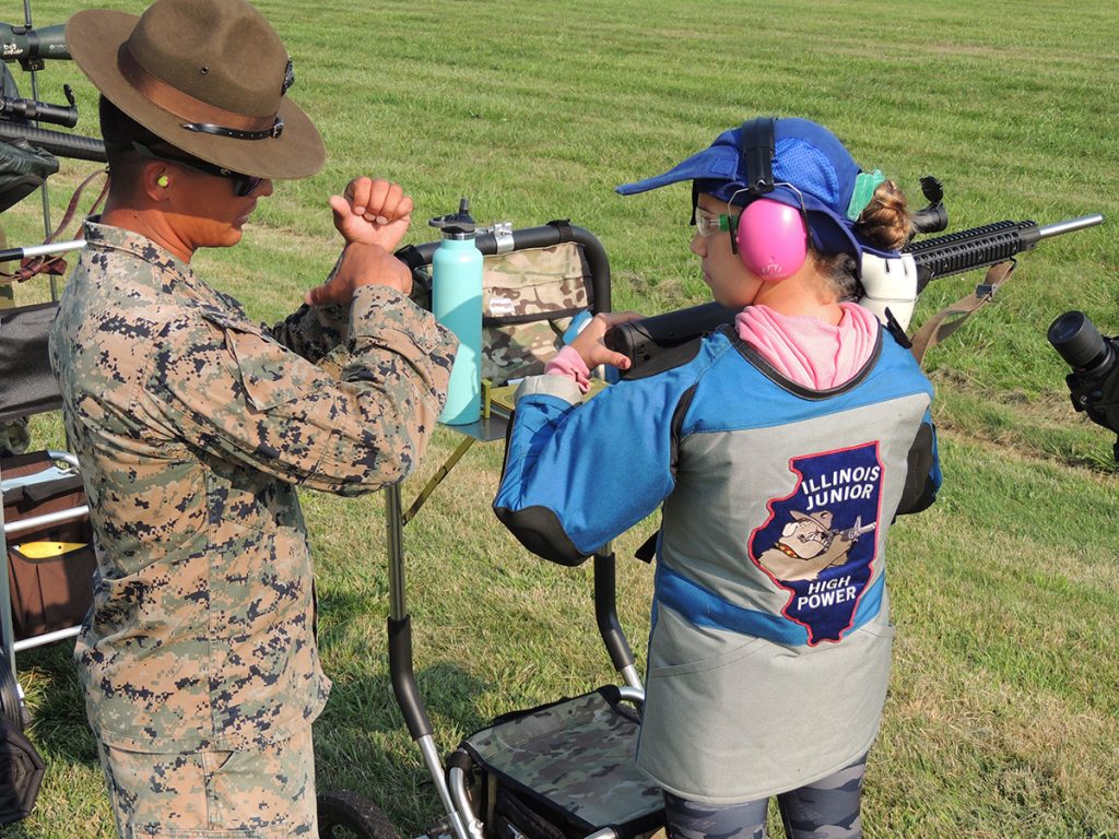 A member of the USMC Rifle Team instructs a junior competitor on the firing line during the USMC Rifle Clinic