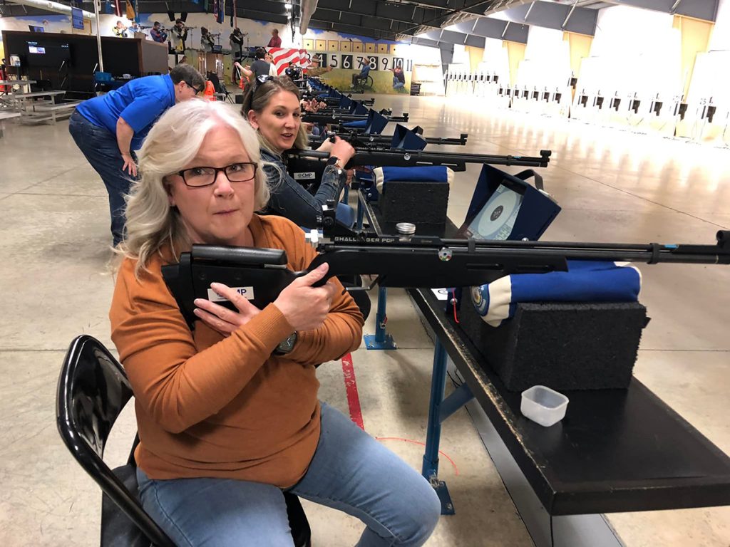 Woman holding rifle on bench at the air gun range.