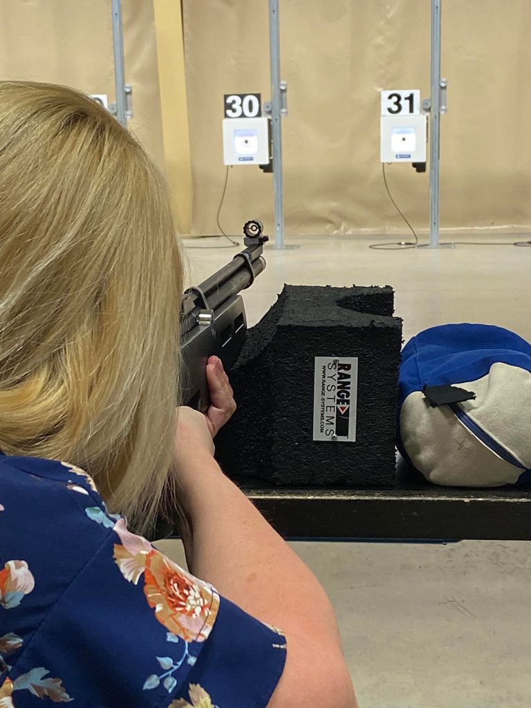 Woman shooting downrange off a bench.