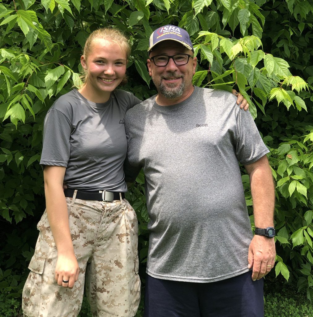 Madelyn poses with Scott on firing range.