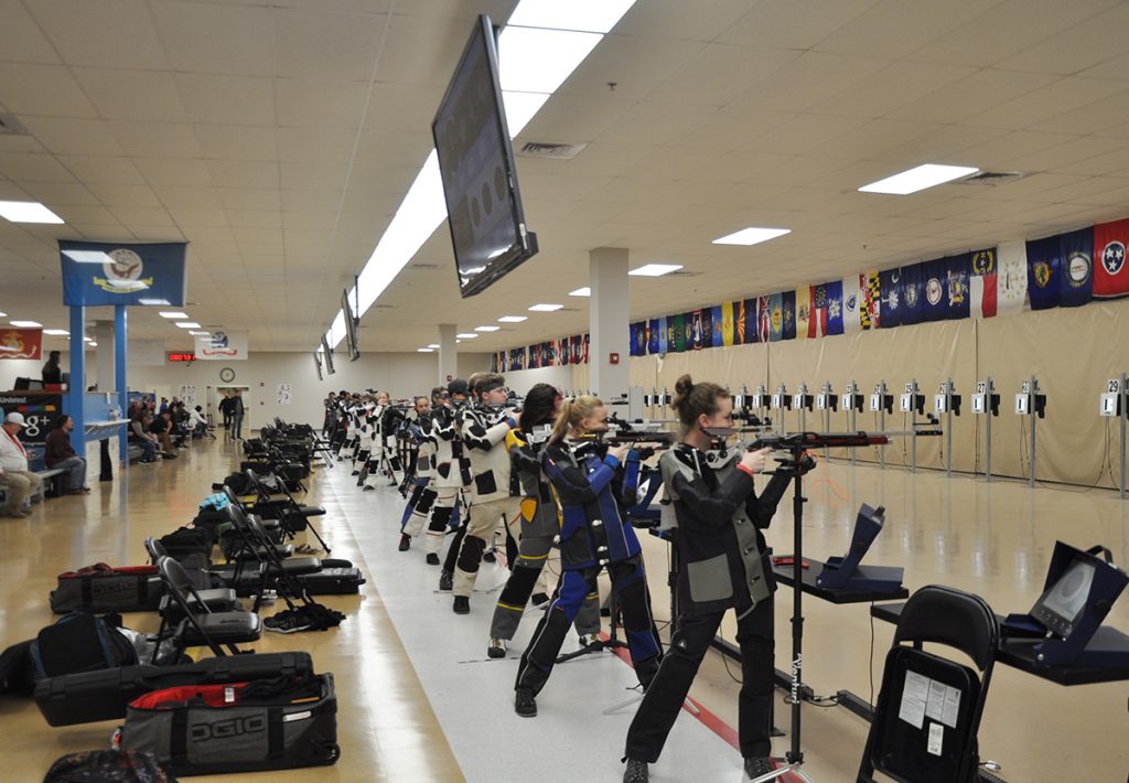 Rifle athletes standing at the firing line.