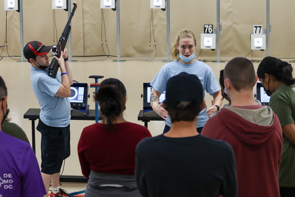 Junior rifle camp counselors instructing campers on the standing position.