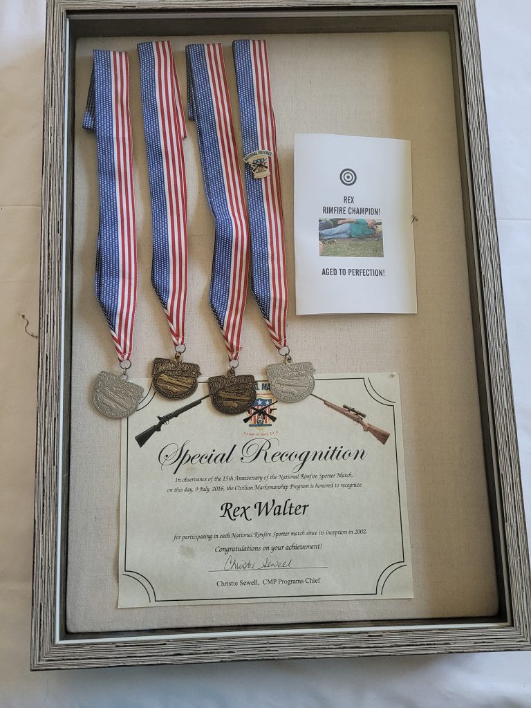 Rex's rimfire medals and a special recognition certificate displayed in a glass case.
