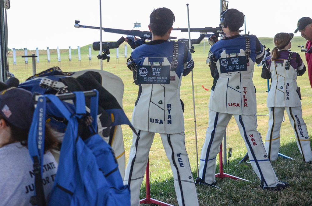 Ryan and Tyler viewed from behind, shooting smallbore outdoors in the standing position.