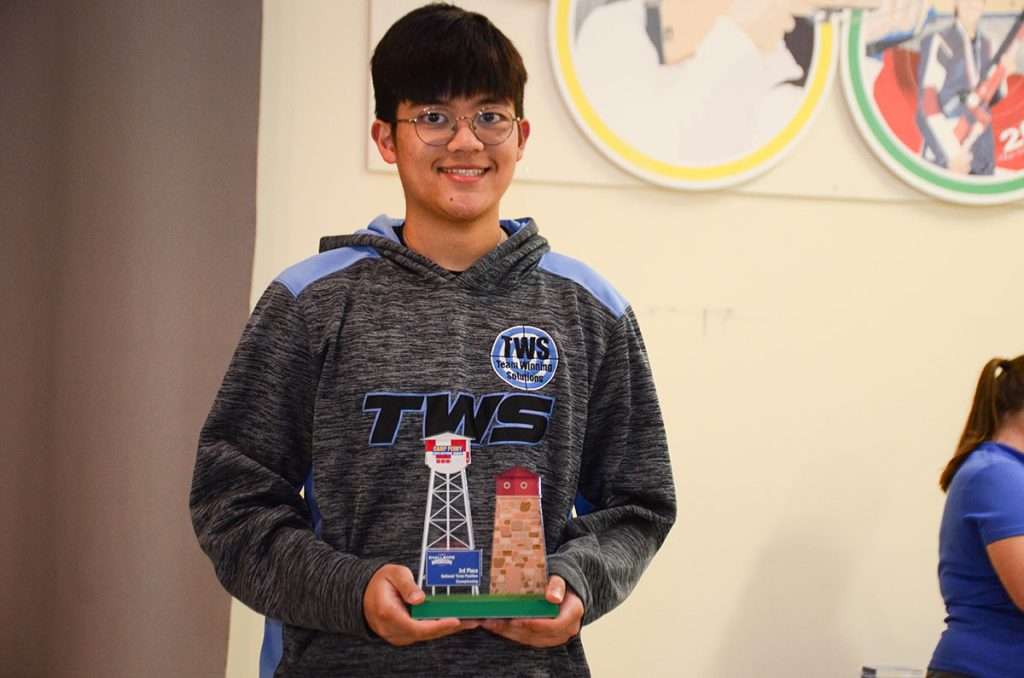 Ryan is smiling for the camera and holding a third place overall trophy for the National Three-Position Smallbore match.