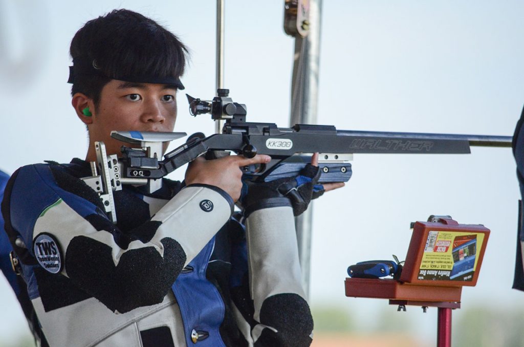 A close up photo of Ryan holding his smallbore rifle in the standing position.