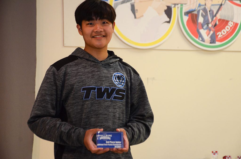 Tyler is smiling for the camera and holding an age group trophy for the National Three-Position Smallbore match. 