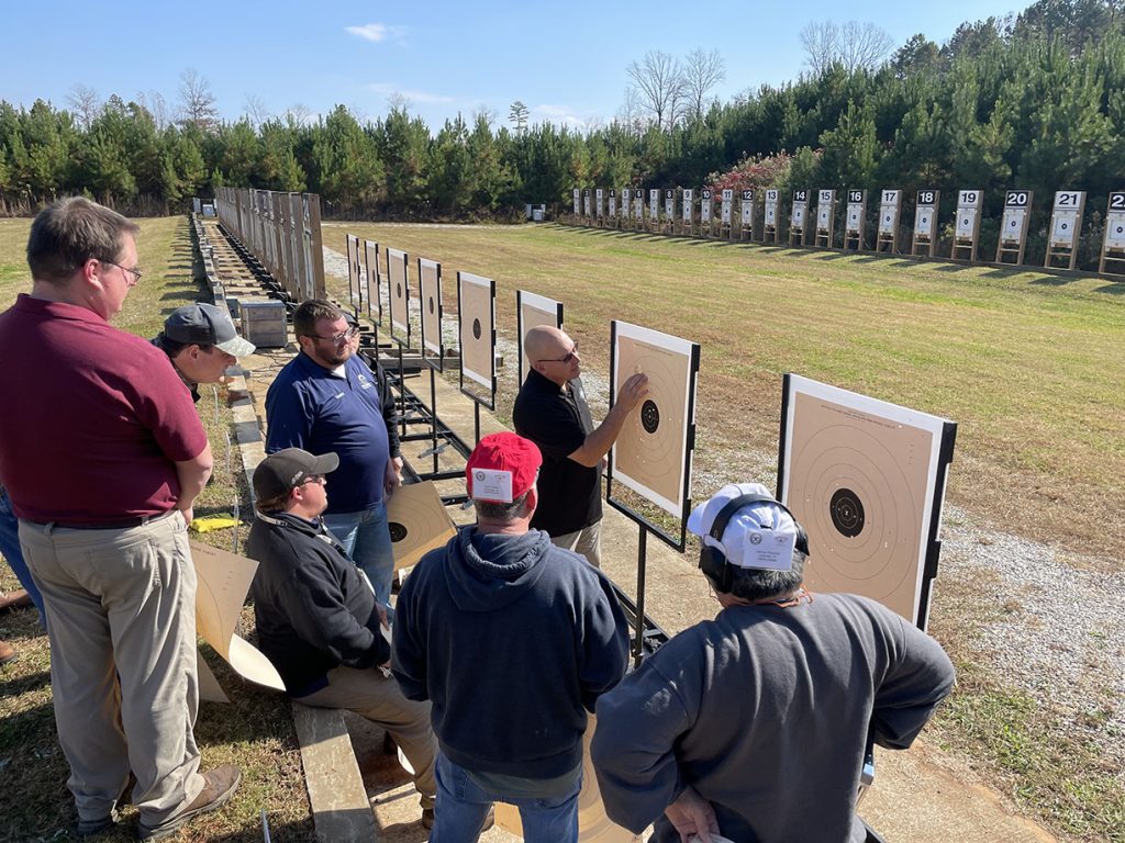 Instructors and participants gathered in front of the target line during an educational course.