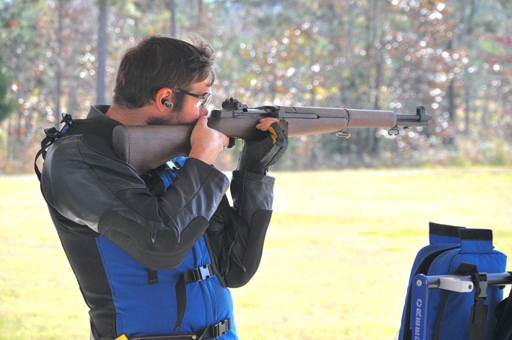 A competitor aims a rifle downrange.