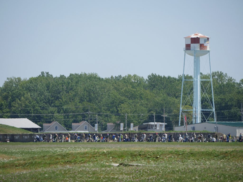A photo of competitors on the firing line with the red and white checkered water tower in the background.