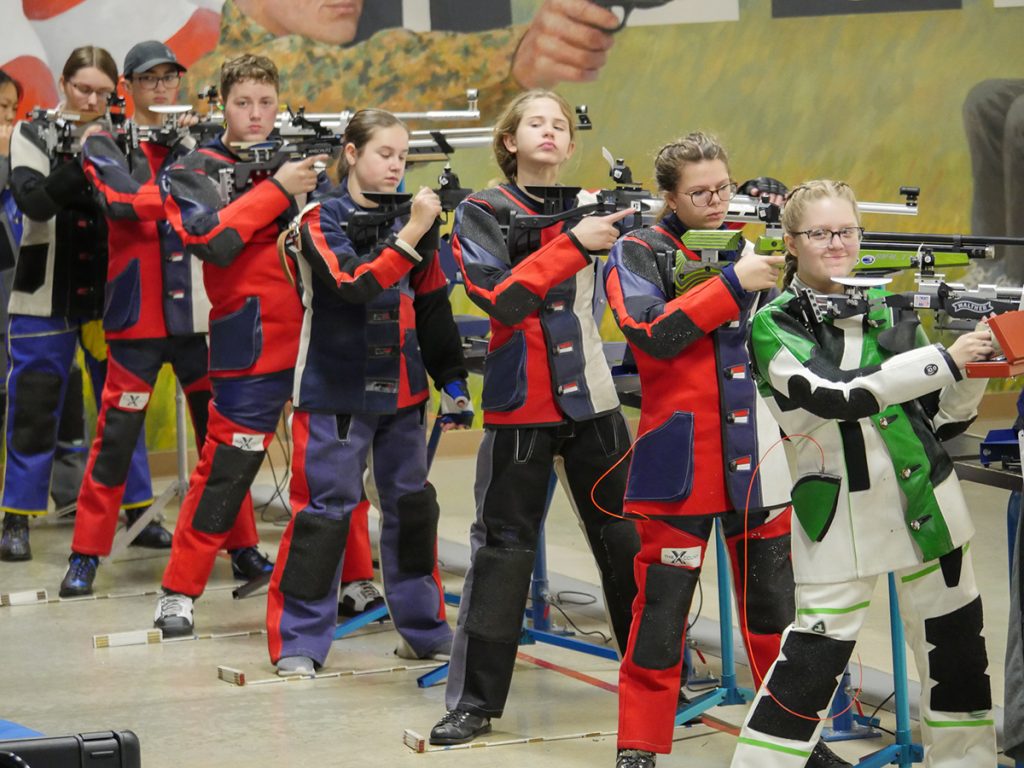 Junior air rifle athletes on the firing line in the standing position.