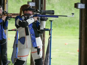 Katrina Demerle on the firing line, aiming her smallbore rifle downrange.