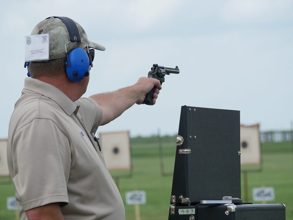 Competitor aiming pistol at targets.