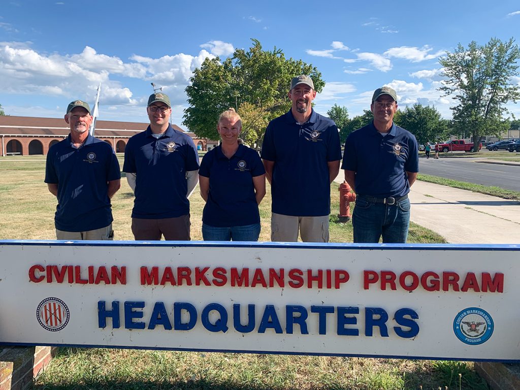 Five CMP instructors for the Advanced Highpower clinic standing behind the CMP Headquarters sign.