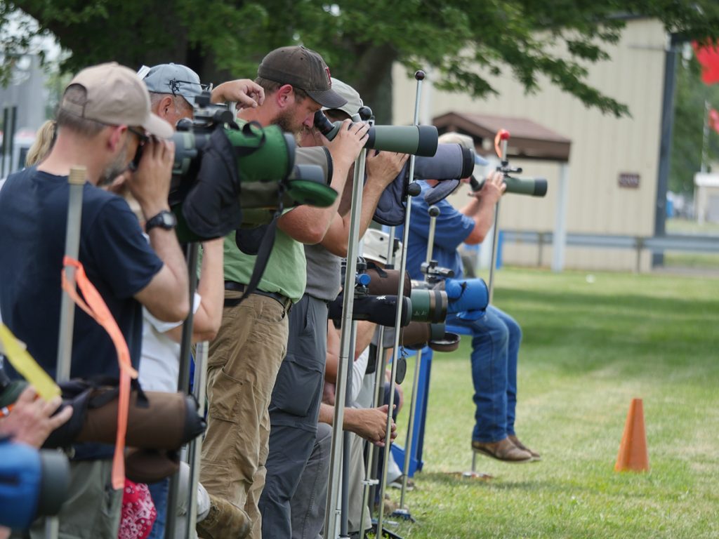 People standing on the firing line reading wind flags through their scopes.