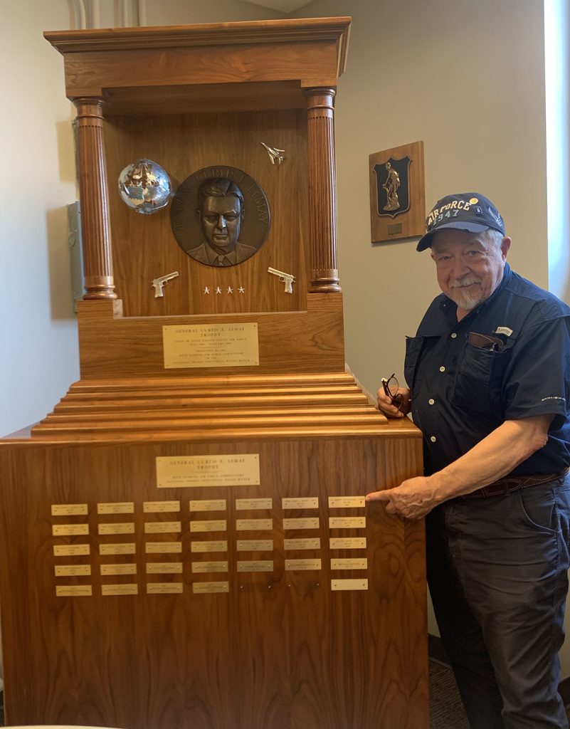 Robert Engelmeier pointing to his engraved name plaque on the Lemay Trophy.