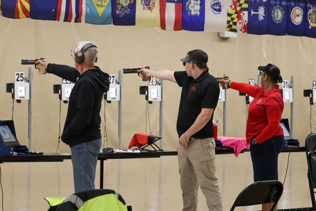 Pistol competitors aim at targets downrange.