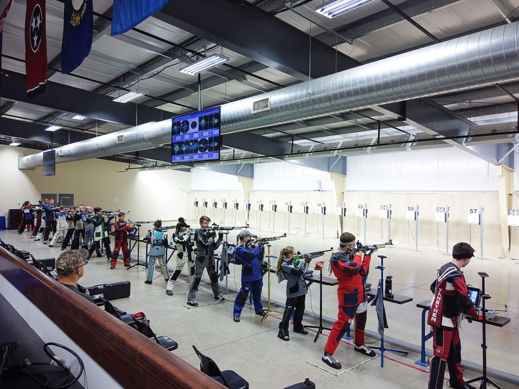 Air rifle athletes on the firing line in the standing position.