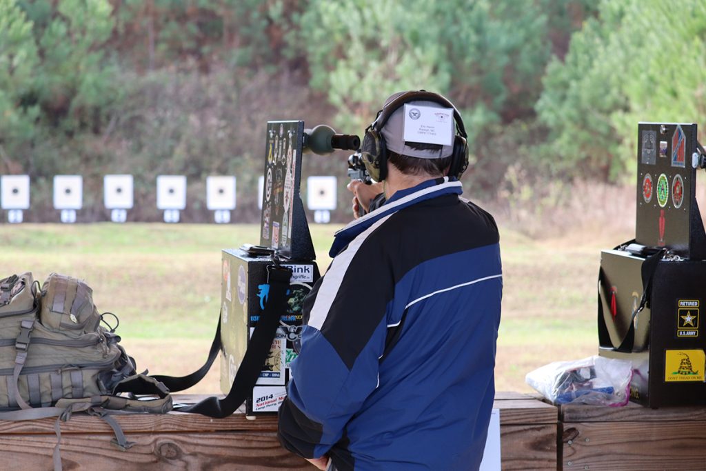 Pistol competitor aiming downrange at targets.