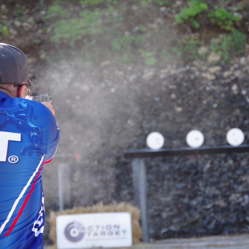 Action Pistol competitor shooting at plates