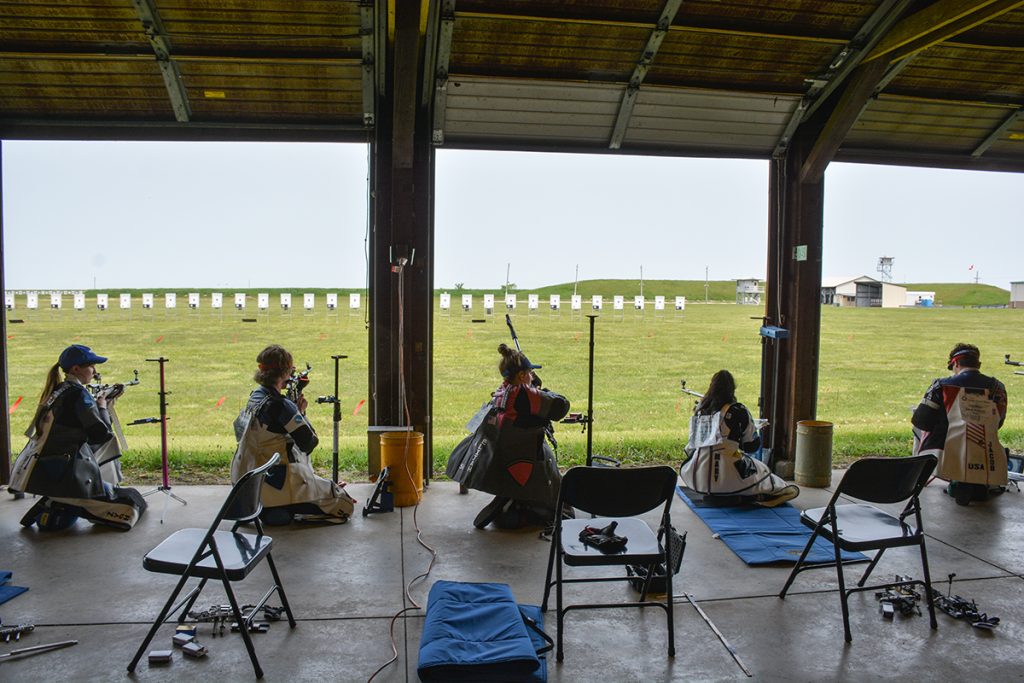 Smallbore competitors in the kneeling position firing shots downrange.