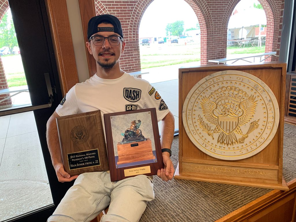 Nick Milev poses with trophy and award plaques.