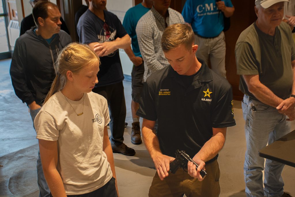 A member of the USAMU pistol team shows a student the M9 pistol.