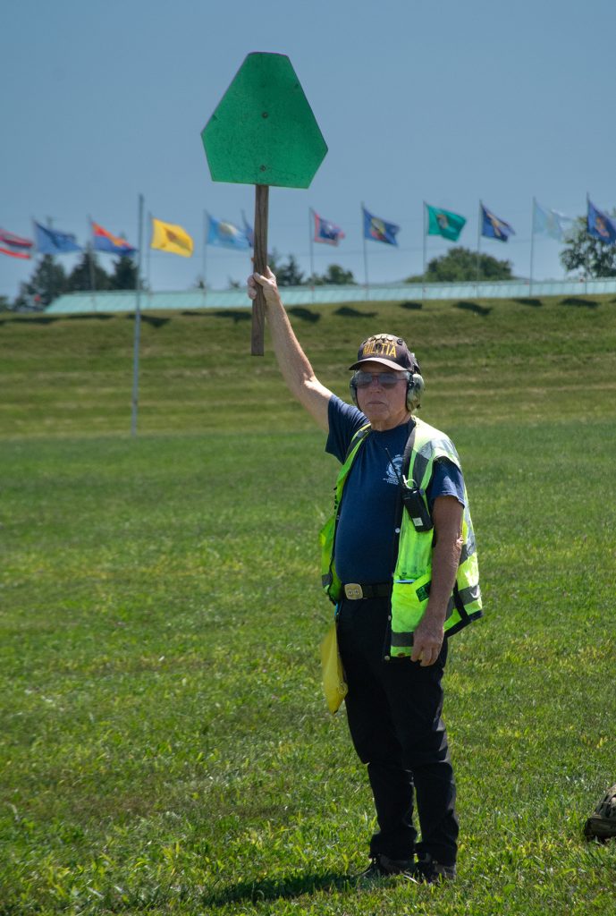 Range officer signals the line is clear with a green paddle.