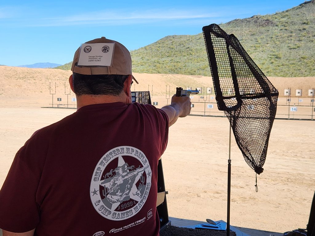 Competitor firing a pistol at the target downrange.