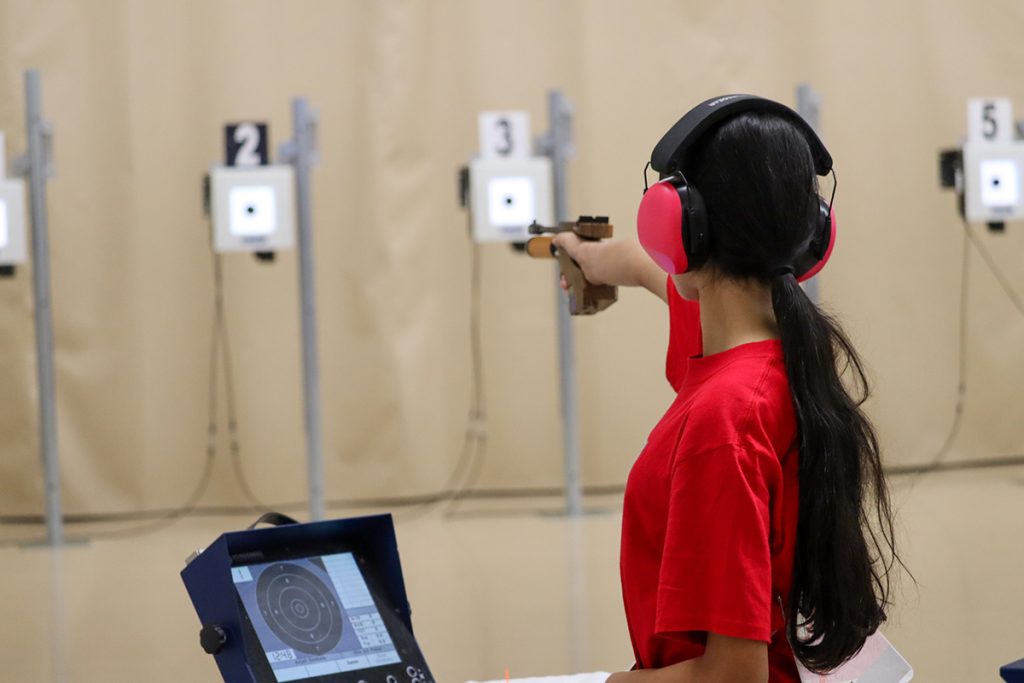 Air pistol competitor aiming at target downrange.