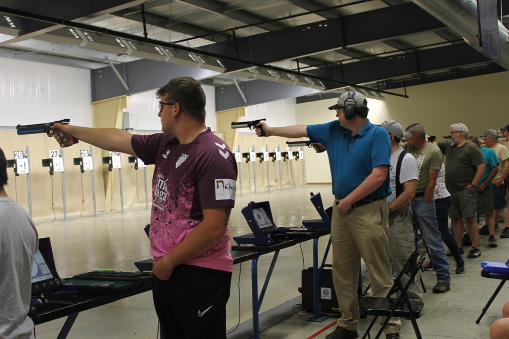 Air pistol competitors aiming at targets downrange.