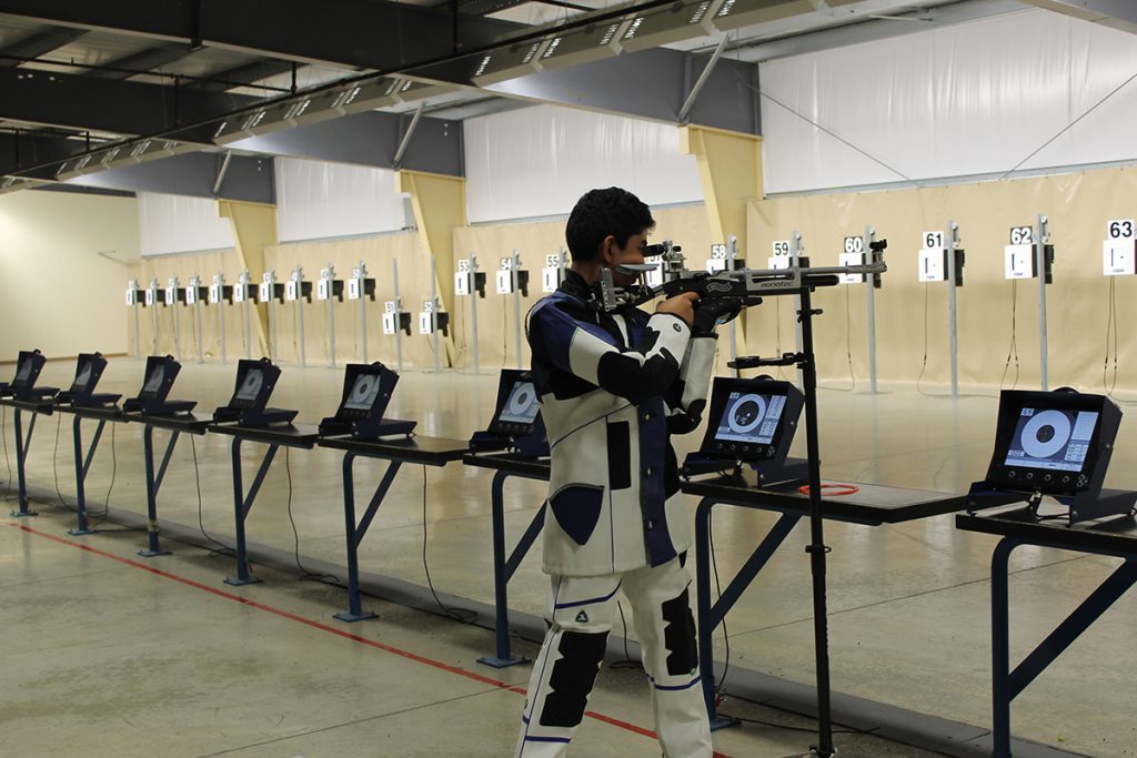 Air rifle competitor taking a shot downrange at target.