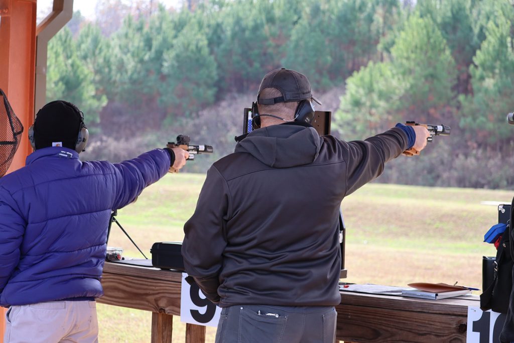 Competitors on the firing line firing their pistols at targets.