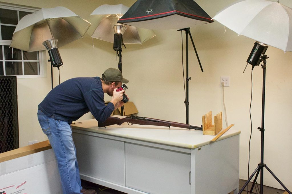 Josh White, an Auction Room employee, photographs a rifle for the Auction Site. The photographs are key in showing the detail of items to customers.