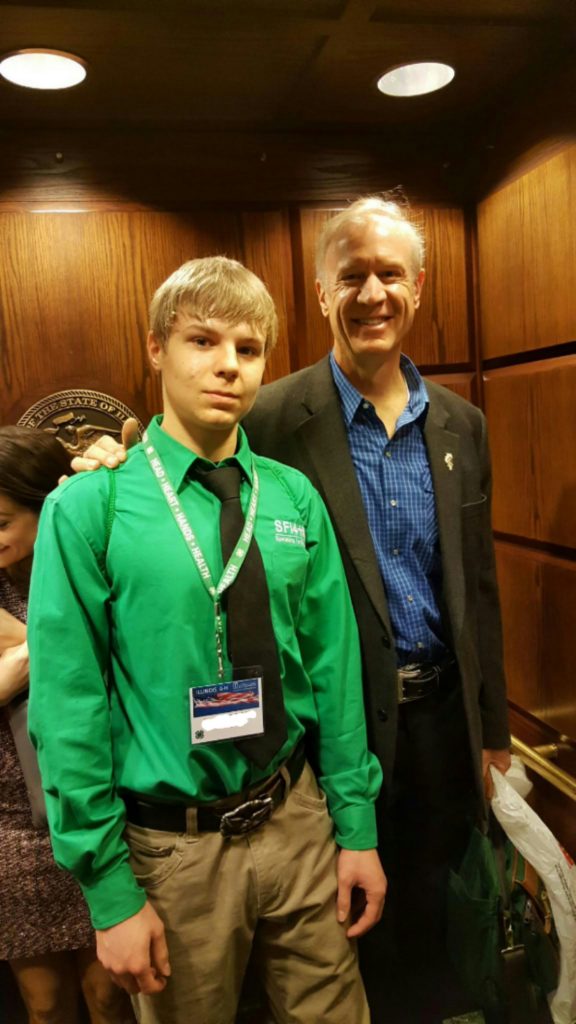 The speaking club member with the Illinois Governor, Bruce Rauner, at the Illinois General Assembly 