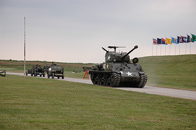 A fleet of vintage vehicles rolled towards the crowd, driven by World War II reenact ors. A M4 Sherman tank led the pack, followed by Toledo-made Willy's Jeeps.